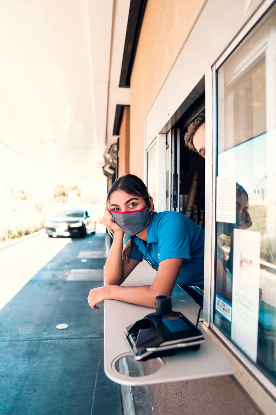 A crew member leaning out of a drive-thru window during a slow moment