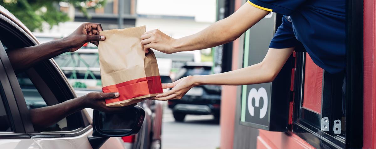 A crew member handing a bag to a customer at a drive-thru window